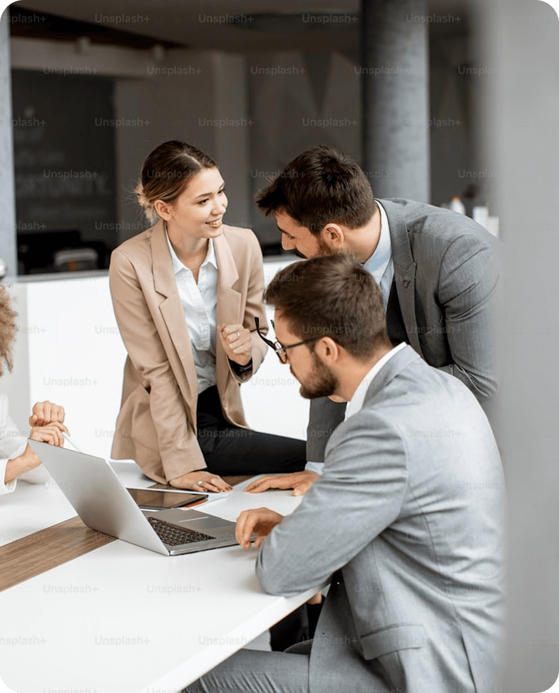 Business professionals collaborating around a laptop at a desk in a modern office.