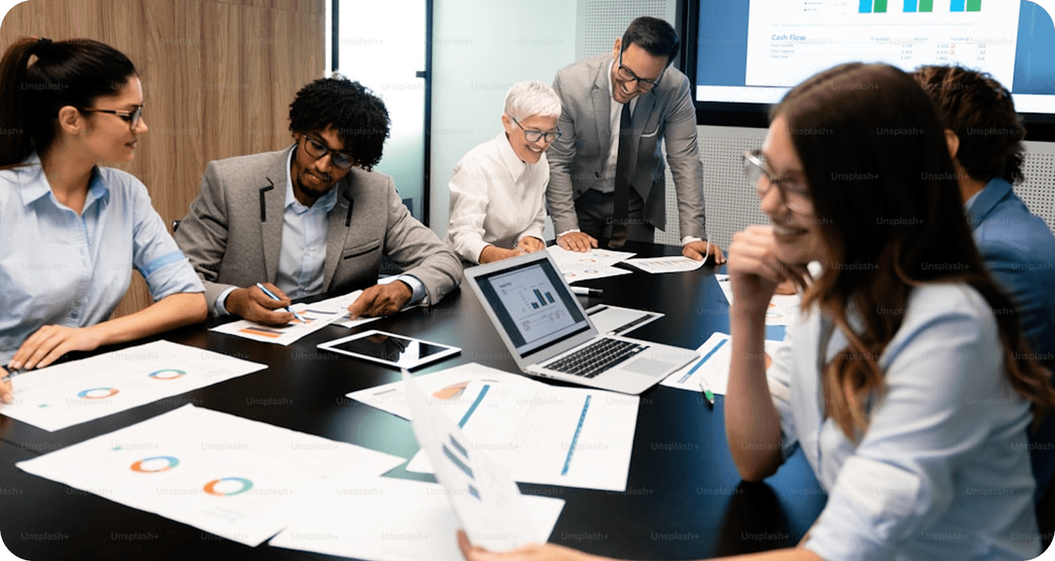 Diverse business team collaborating around a conference table with financial charts, reports, and a cash flow dashboard.