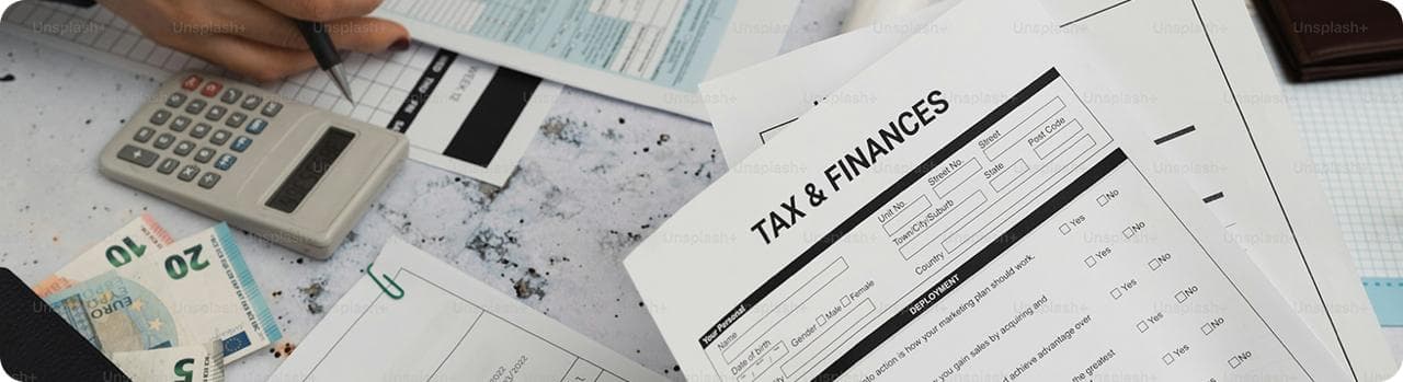 Desk with tax and finance documents, calculator, and currency notes for financial planning.