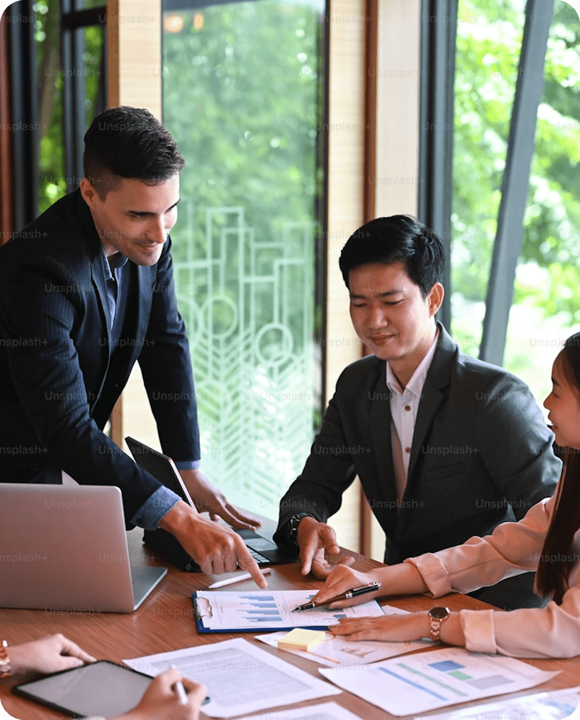 Technology consultants collaborating in a modern office with documents and a laptop.